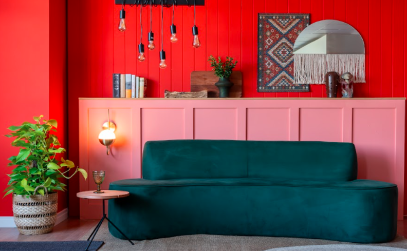 cor de parede para sala com tons vibrantes como vermelho e rosa, além de sofá azul e diversos itens de decoração.