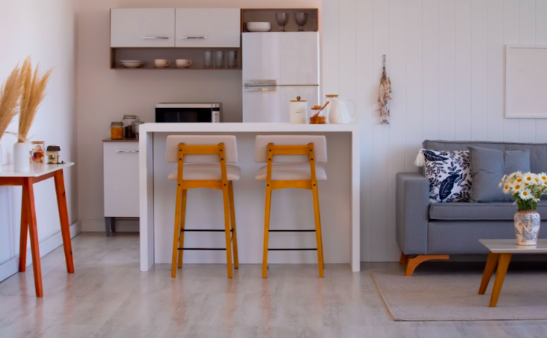 cores neutras na casa, em um ambiente de cozinha e sala de estar com tons claros, além de itens decorativos em tons mais vibrantes.