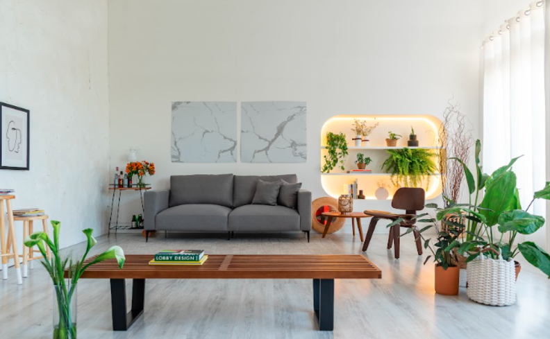 paleta de cores neutras para a sala de estar, com sofá cinza, paredes brancas e itens decorativos minimalistas e vasos com plantas.