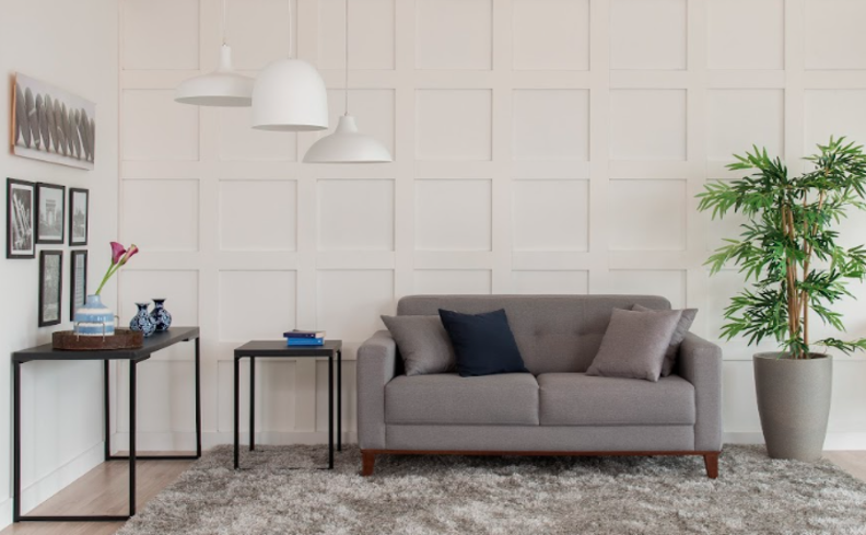 dicas para saber quais são as cores neutras para decoração, com sala de estar com sofá cinza, tapete cinza e mesas de madeira, além de itens decorativos básicos.