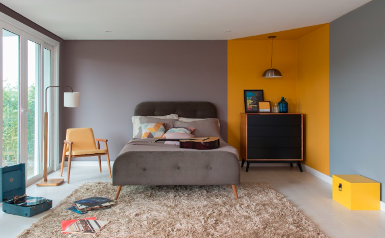 decoração de quarto de casal com tons cinza, amarelo, bege e os móveis em preto.