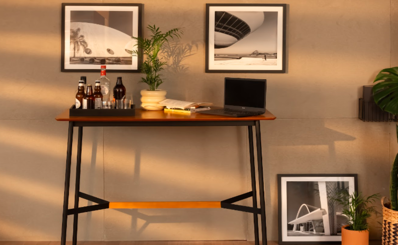 escrivaninha estilo industrial com a estrutura de metal em preto, base de madeira escura, quadros e diversos itens de decoração para complementar.