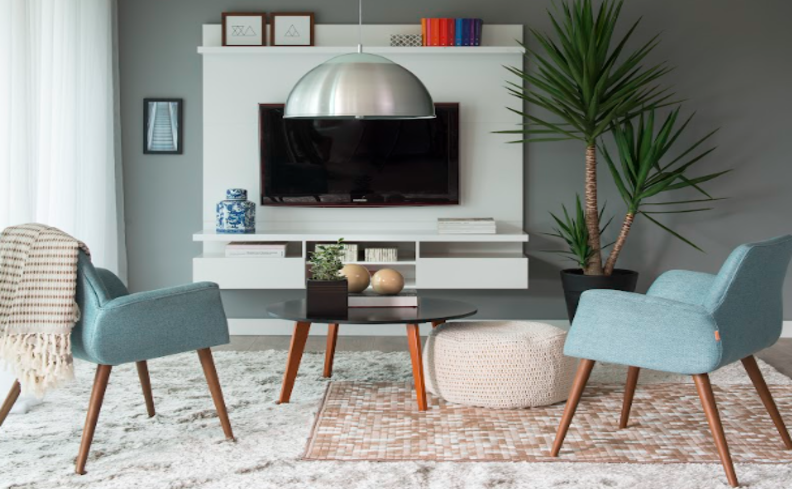 modelos de tapetes para sala de estar com poltronas, painel de TV, lustre pendente e diversos itens de decoração.