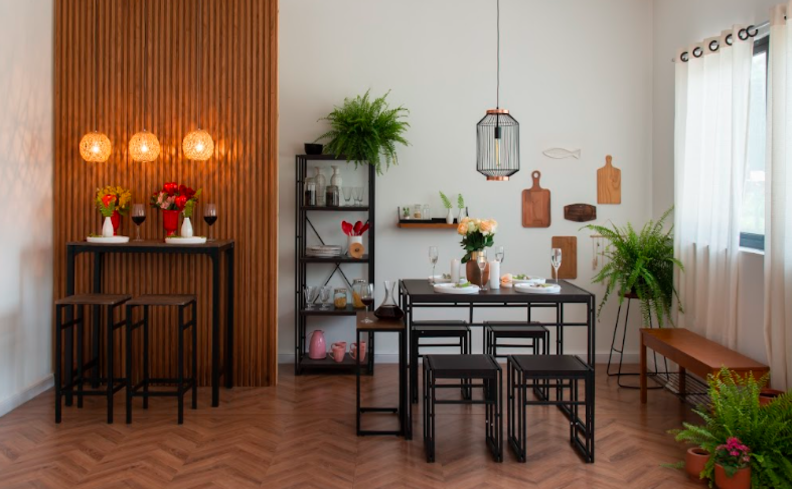 sala de jantar estilo industrial com mesa e bancos com a estrutura de metal preta, estante de metal, lustre pendente e alguns tons de madeira escuro nos itens decorativos.