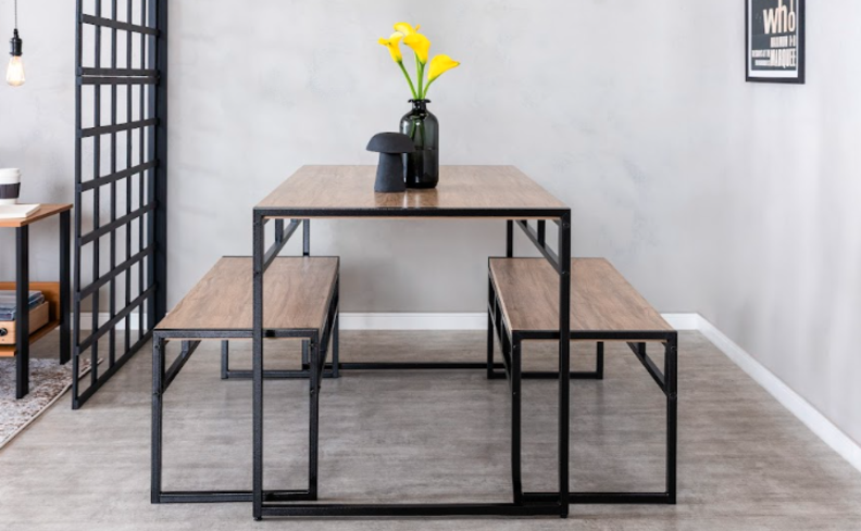 sala estilo industrial com mesa com estrutura preta de metal, assim como os bancos e tons de madeira escuro na base da mesa, além de vaso decorativo.