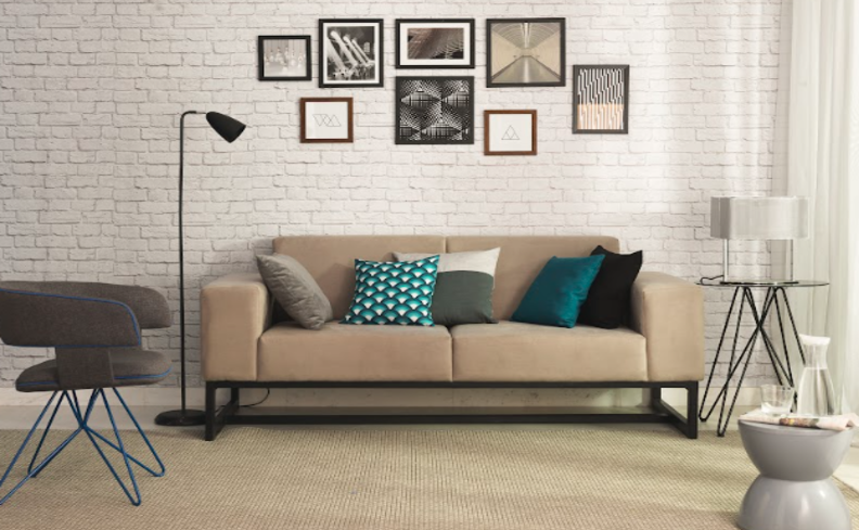 sala industrial com sofá cinza, luminária de chão preta, diversos quadros, parede de tijolinhos e diversas almofadas para complementar.