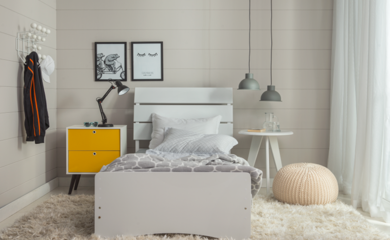 tapete para quarto com cama, puff, mesa de cabeceira, quadros decorativos, lustre pendente e outros itens decorativos.