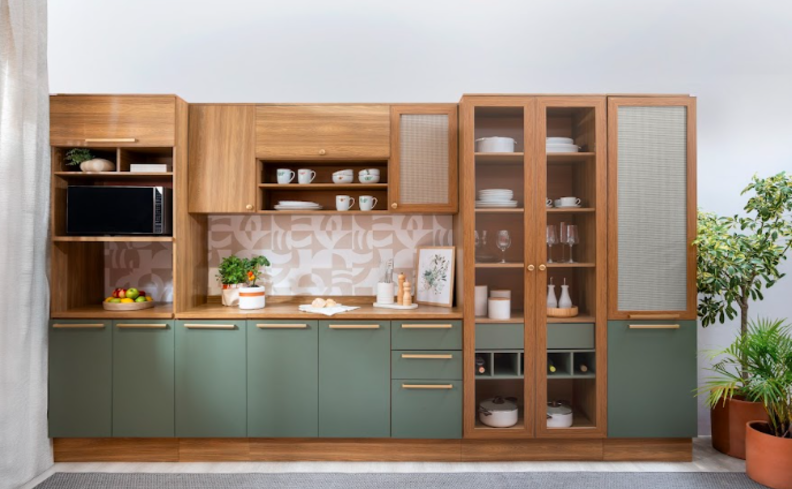 armário de cozinha modulado em um ambiente completo com armários nas cores verde e madeira, com diversos itens como pratos, vasos com plantas, copos, bowls e muito mais.