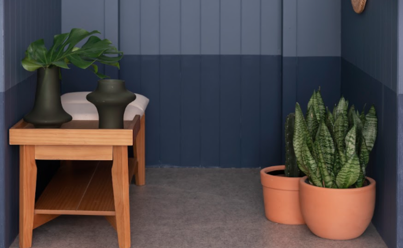 banco sapateira para hall de entrada, além de vasos com plantas e almofadas.