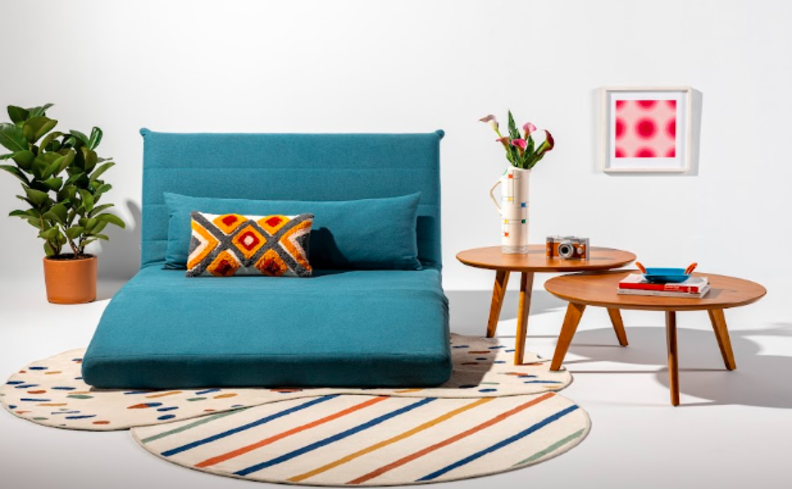 poltrona cinema em casa para assistir filmes e séries com muito conforto e beleza, com poltrona azul com almofadas, tapete e duas mesas de apoio.