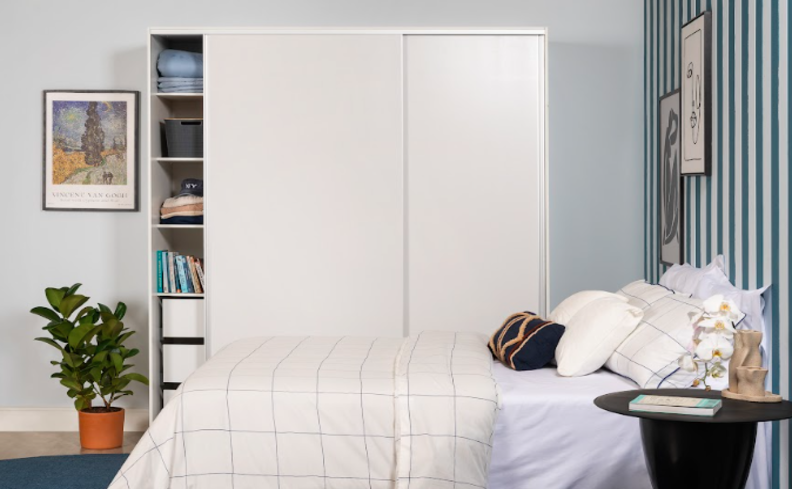 decoração quarto casal moderno com guarda-roupa branco, cama com roupa de cama branca com tons de azul nos itens decorativos para criar contrastes.