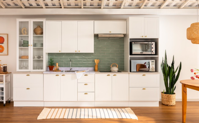 decoração apartamento alugado em uma cozinha com armários modulares, tapete, uma parede verde, itens decorativos como vaso com plantas e quadros.