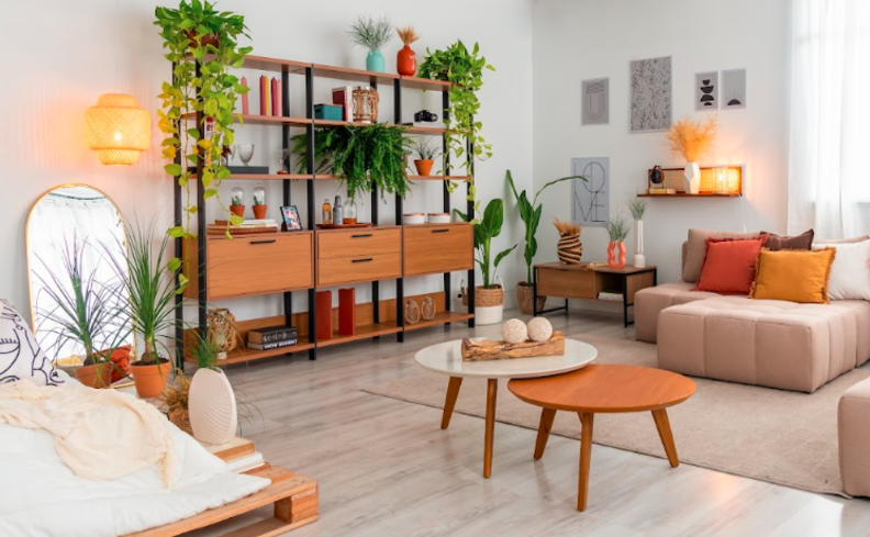 apartamento pequeno decorado em uma sala de estar com estante de madeira e aço, com diversos itens decorativos, além de mesas de centro, sofá modular, espelho apoiado na parede e diversos quadros colados com fita para evitar furos nas paredes.