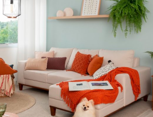 decoração apartamento alugado com sala de estar com parede azul, sofá modular, almofadas, capa de almofada e diversos itens de decoração.