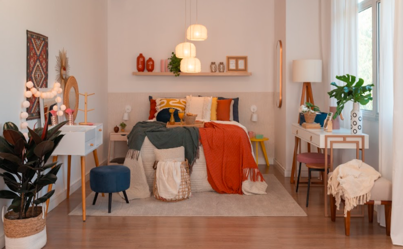 quarto de hóspedes multifuncional com cama, puff, penteadeira, escrivaninha, prateleiras, luminárias e diversos itens decorativos.