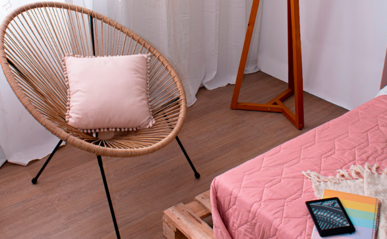 quarto de hóspedes com cantinho para leitura com poltrona, almofada, luminária de chão e cama posta.