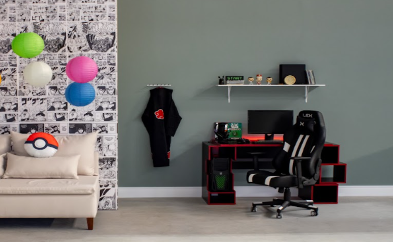 quarto gamer simples com mesa para computador preta, cadeira gamer preta e branca, prateleira com diversos itens decorativos, sofá ao lado e uma parede com papel de parede estampado para complementar o ambiente.