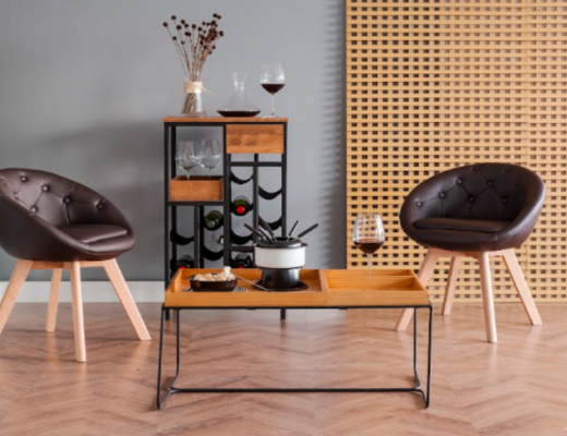 dicas para fazer fondue em casa em um ambiente com mesa de apoio, duas poltronas com pés palitos e estofados marrom, um móvel com vinho e a mesa com panela de fondue e vinhos.