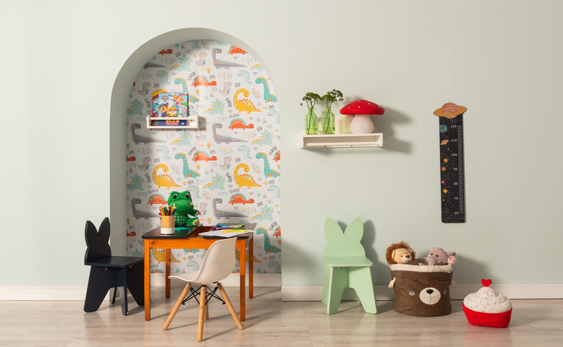 o que fazer nas férias escolares e casa no quarto da criança com parede pintada com dinossauros, mesa e cadeiras infantil e diversos itens decorativos.