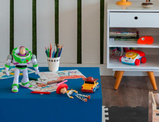 quarto de brinquedos com diversos bonecos, mesa de centro azul, mesa de cabeceira branca, tapete e diversos itens decorativos.