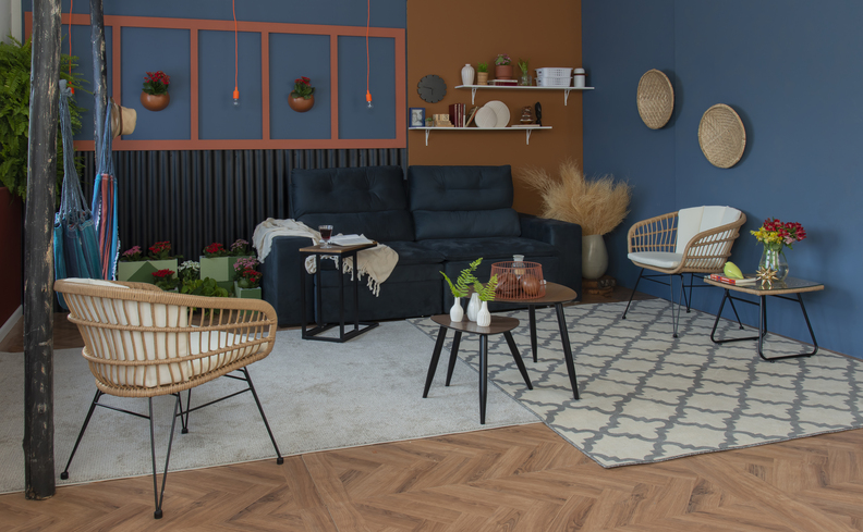 simples decoração de casa com sala de estar com parede azul, tapete cinza, diversas poltronas, sofá azul marinho e itens decorativos para complementar.