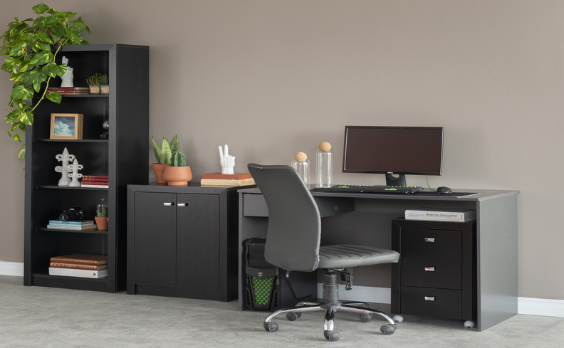 ideias para escritório home office com escrivaninha grande na cor preta com diversas gavetas, gaveteiro, monitor, cadeira de escritório cinza com rodinhas, além de diversos itens decorativos.