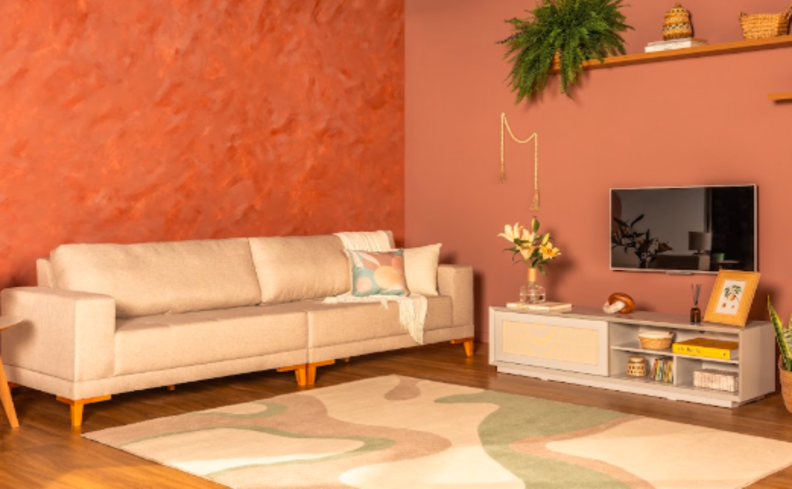 manta de sofá branca em um sofá de três lugares branco na sala de estar com rack, televisão presa na parede, prateleira com itens decorativos e tapete no chão.