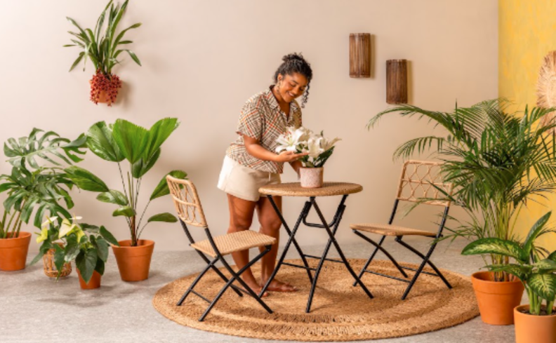 duas cadeiras para varanda pequena, além de tapete redondo, mesa dobrável redonda e diversos vasos com plantas.
