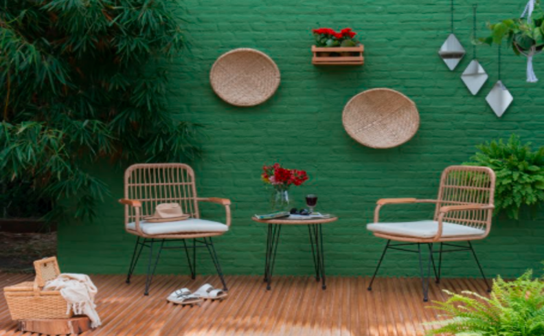 poltronas para varanda, além de uma mesa de apoio redonda e itens decorativos nas paredes e sobre a mesa.