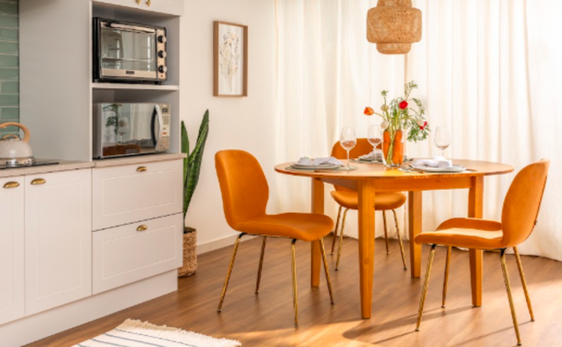 mesa de jantar black friday em madeira e três cadeiras amarelas, armários de cozinha brancos e lustre pendente.