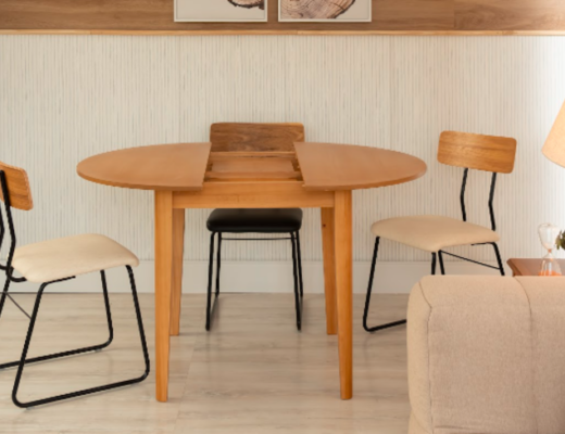 mesa de jantar extensível de madeira com três cadeiras na sala de jantar, além de sofá e quadros decorativos no ambiente.