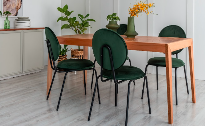 mesa extensível retangular na sala de jantar, além de três cadeiras verdes, vasos com plantas e adornos de mesa.