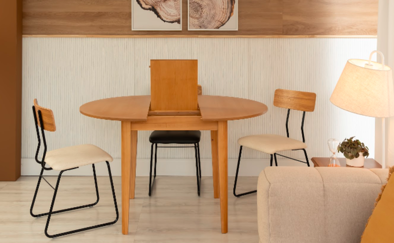 mesas para pequena com extensão, três cadeiras, sofá, abajur e quadros decorativos.